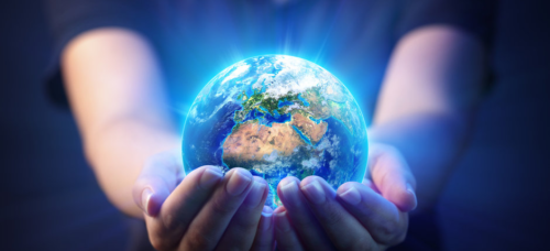 glowing hands holding glowing planet earth in white blue light